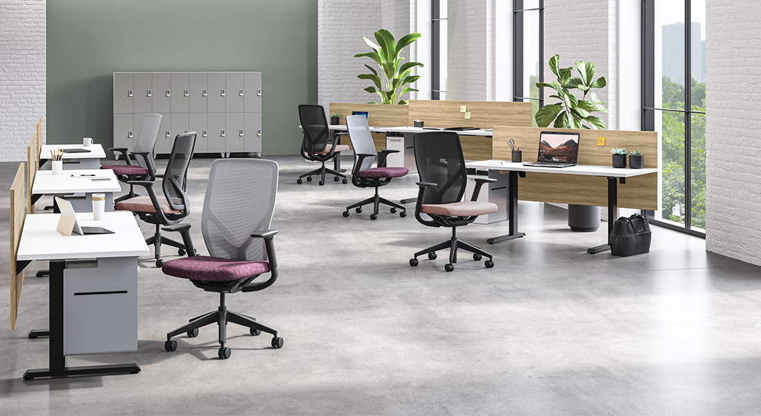 Large trendy and open modern office space with individual work stations using variable height desks and ergonomic rolling office chairs