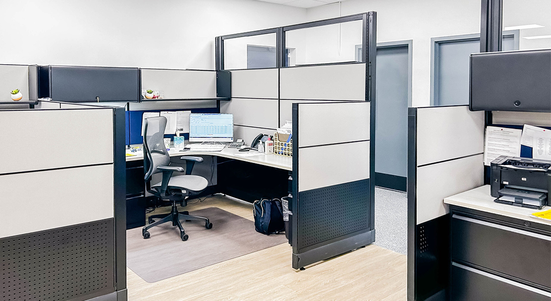 Updated office space cubicle with modular walls, adjustable storage, ergonomic chair, and protective floor mat