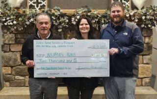 River Bend Business Products employee holding up a donation of $2,000 to the NUMAS Haus with representatives from NUMAS