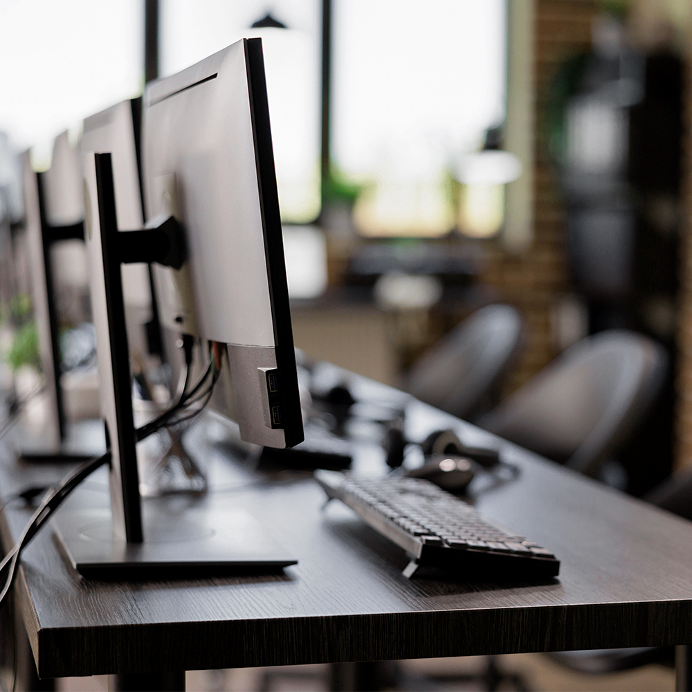 Modern computers in a clean environment lined up on a workstation surface with keyboards ready for use