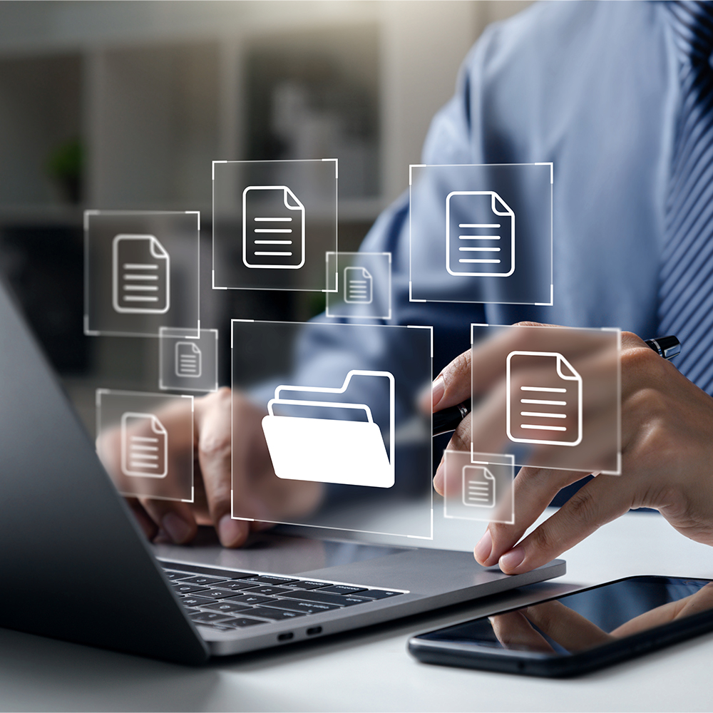 Business person working on a laptop with artificial overlay graphics representing digital documents and digital file organization